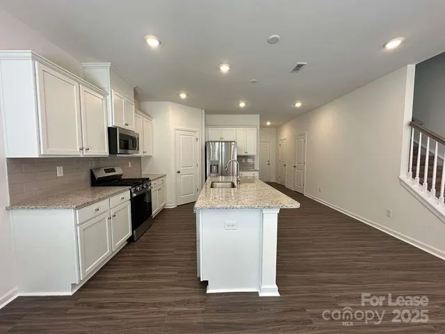 a large kitchen with kitchen island a sink dishwasher stove with wooden floor