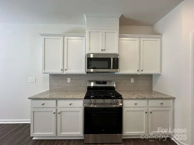 a kitchen with granite countertop white cabinets and stainless steel appliances