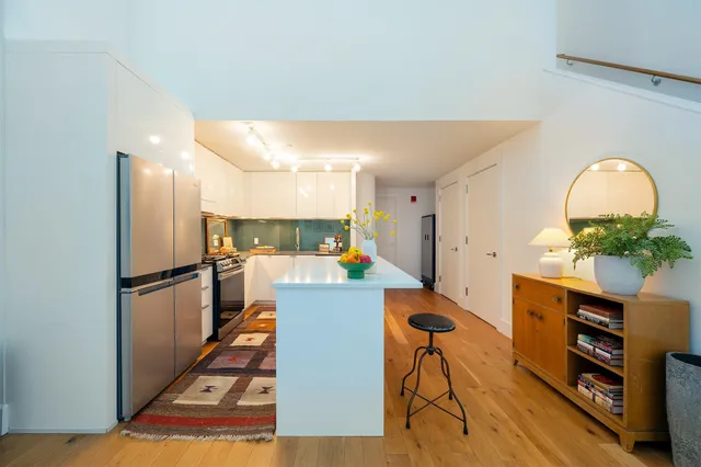 a kitchen with stainless steel appliances a refrigerator a stove a sink dishwasher and a dining table with wooden floor