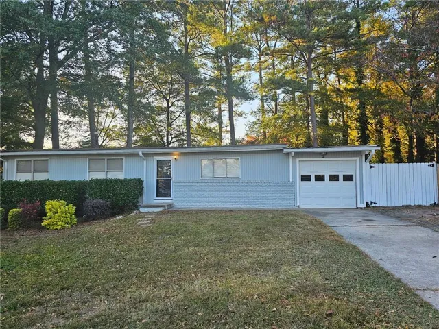 a view of a house with a yard and a large tree