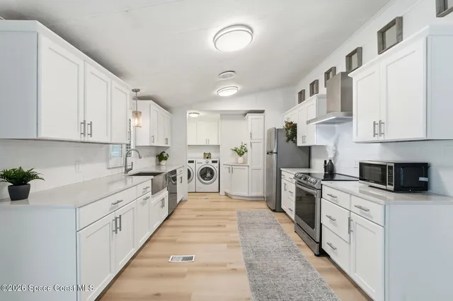 a kitchen with stainless steel appliances granite countertop a refrigerator a stove a sink and white cabinets