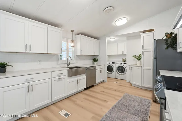 a kitchen with stainless steel appliances granite countertop a sink dishwasher a stove and white cabinets with wooden floor