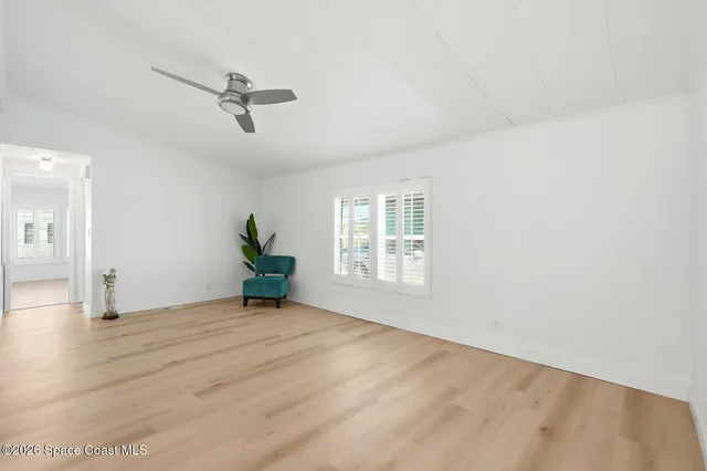 a view of an empty room with a window and wooden floor