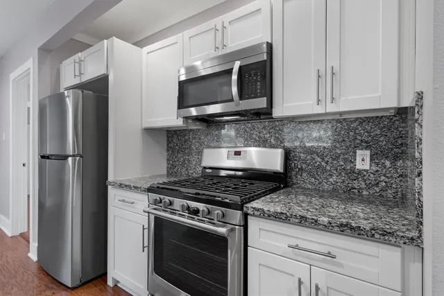 a view of an empty room with wooden floor and a ceiling fan