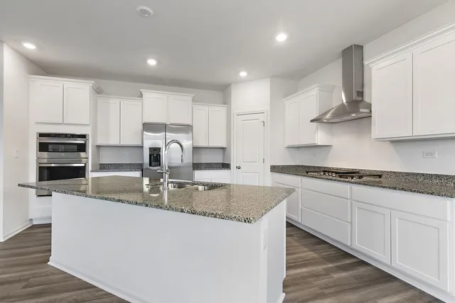 a kitchen with stainless steel appliances granite countertop a sink stove oven and white cabinets with wooden floor