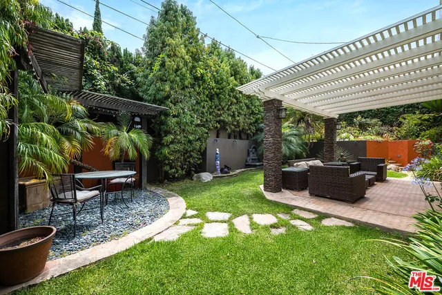 a view of a patio with table and chairs potted plants and large tree
