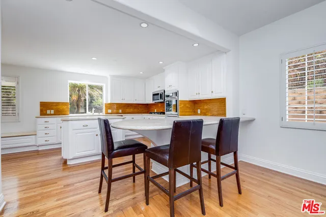 a kitchen with a table chairs refrigerator and wooden floor