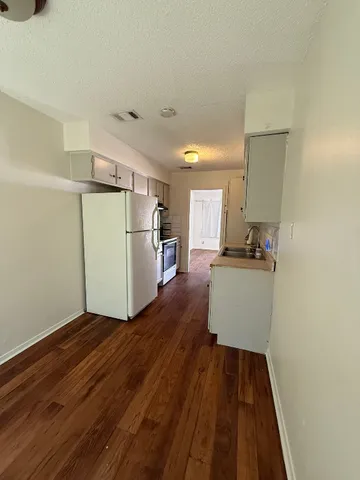 a view of wooden floor and a refrigerator in a kitchen
