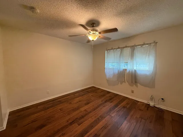 an empty room with wooden floor and fan