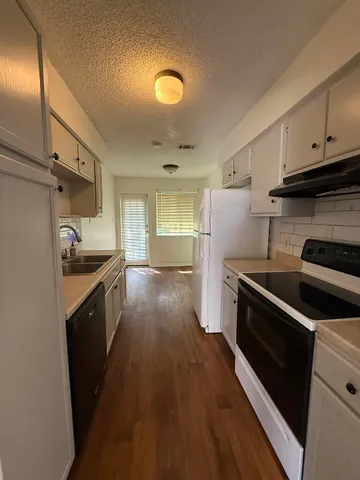 a kitchen with granite countertop a sink cabinets and stainless steel appliances
