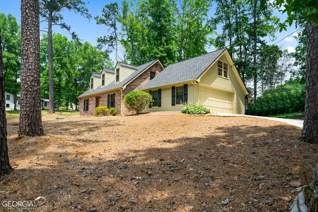 a view of house with outdoor space and trees in the background