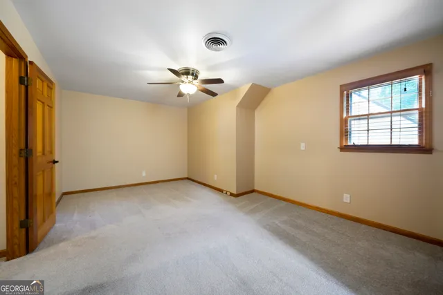 an empty room with windows and chandelier fan