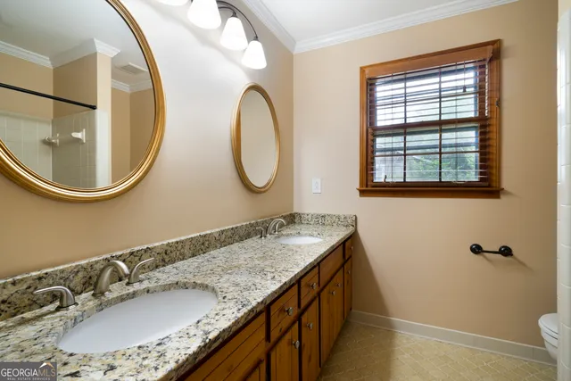 a bathroom with a granite countertop double vanity and a mirror