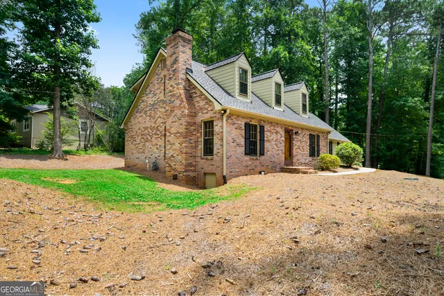 a front view of a house with a garden and trees