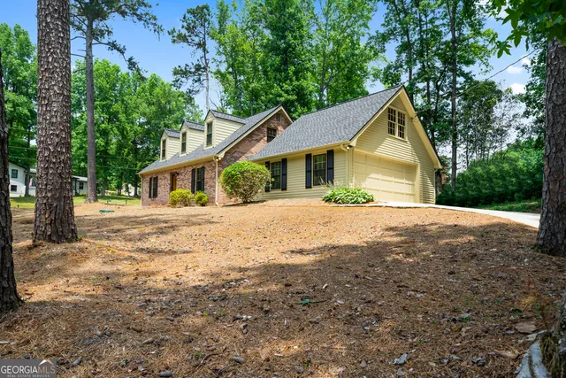 a view of house with outdoor space and trees in the background