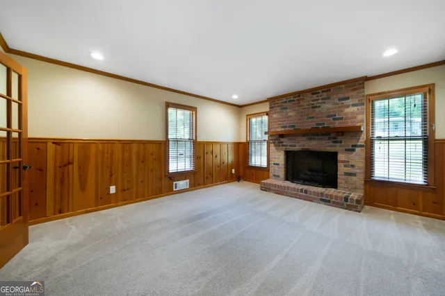 an empty room with windows and fireplace