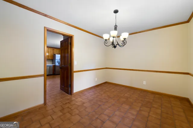a view of a livingroom with a chandelier fan and kitchen view