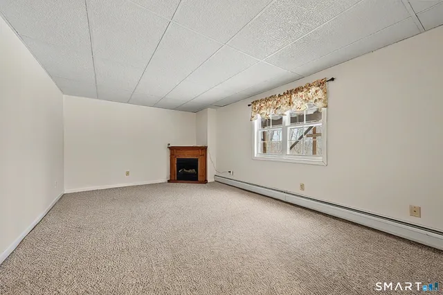 a view of an empty room with a fireplace and a window