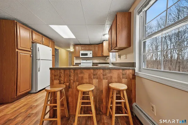 a kitchen with stainless steel appliances granite countertop a refrigerator a stove a sink dishwasher and wooden cabinets with wooden floor