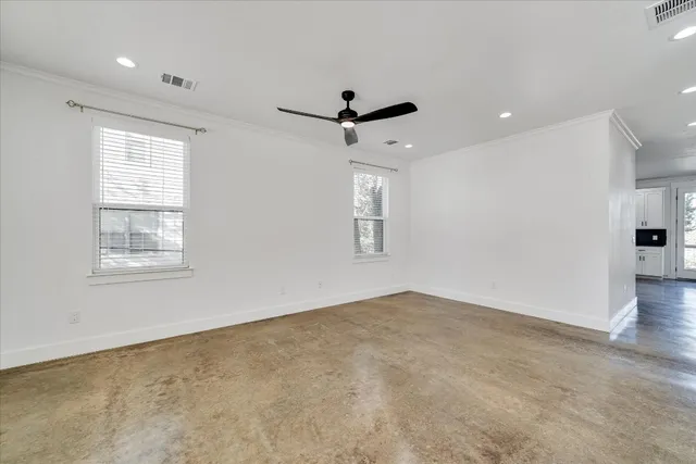an empty room with windows and fan