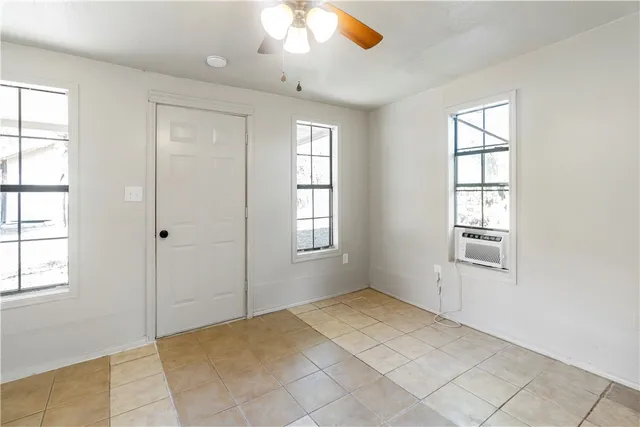 a view of an empty room with window and chandelier fan