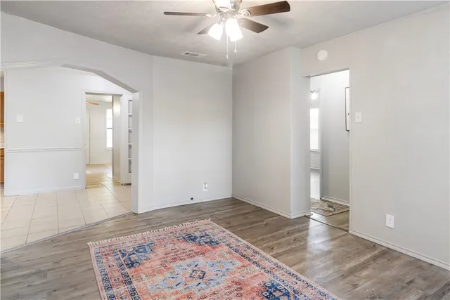 an empty room with wooden floor and a ceiling fan