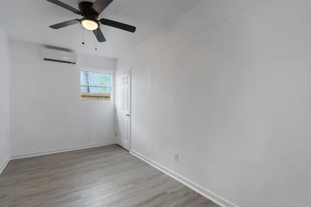 an empty room with wooden floor and ceiling fan