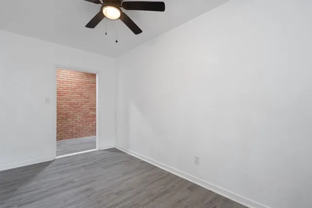 a view of empty room with wooden floor and chandelier fan