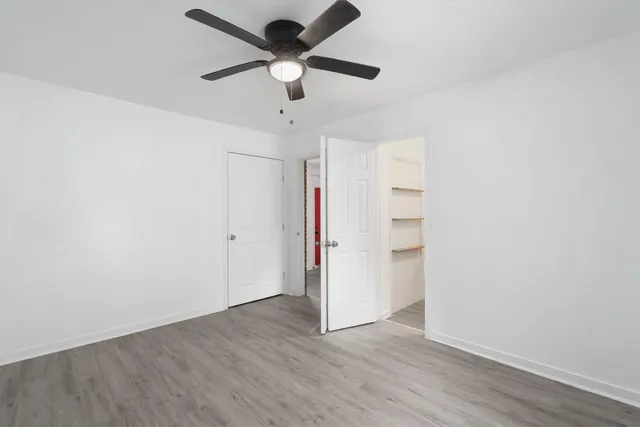 an empty room with wooden floor and ceiling fan