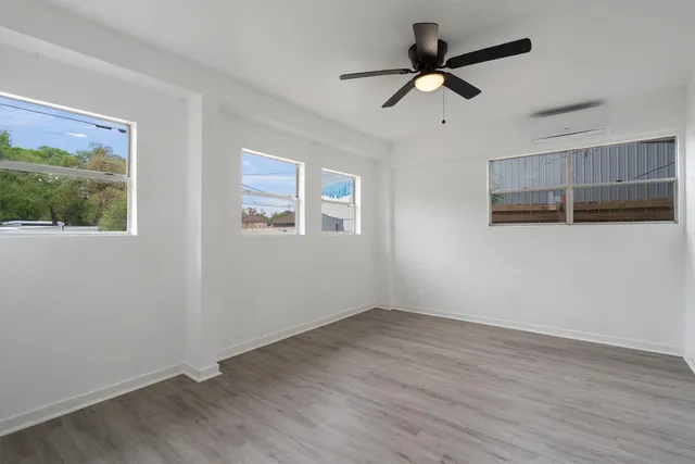 a view of empty room with wooden floor and ceiling fan