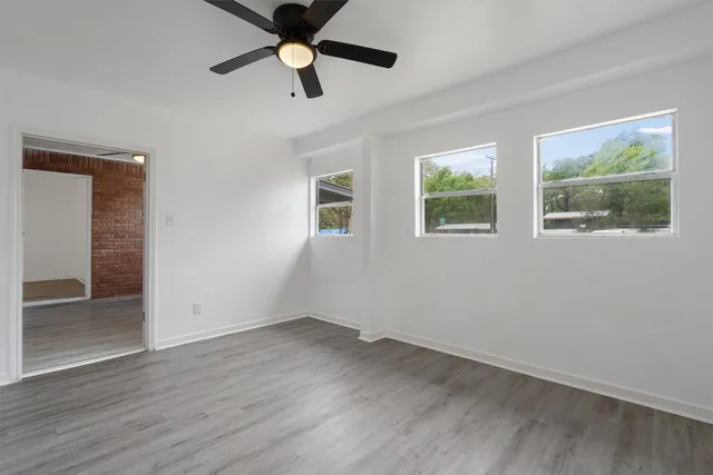 a view of empty room with wooden floor and fan