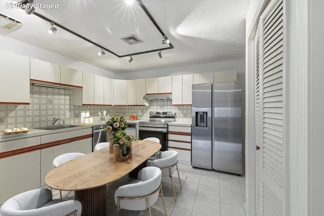 a kitchen with stainless steel appliances granite countertop a sink a stove a refrigerator cabinets and chairs