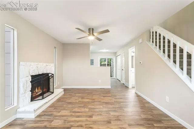 a view of an empty room with wooden floor and a fireplace
