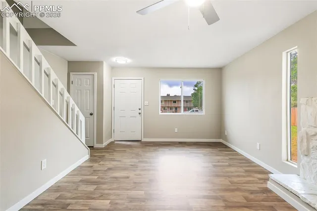 a view of an empty room with wooden floor and a window