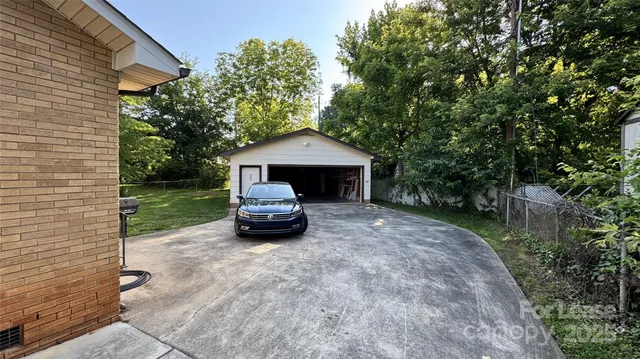a view of a backyard with plants and large tree