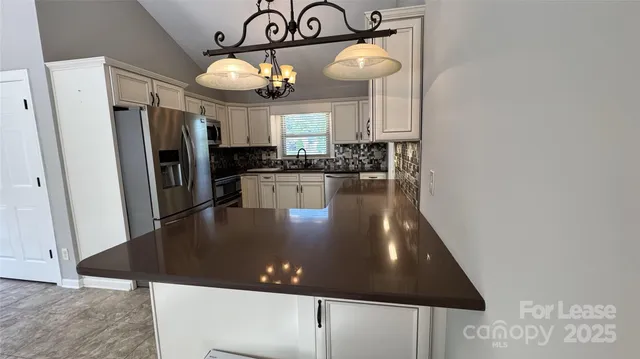 a kitchen with stainless steel appliances granite countertop a refrigerator a stove a sink and a microwave