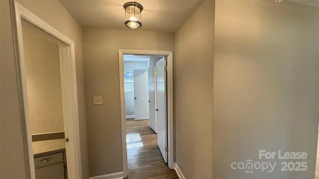 an empty room with wooden floor chandelier fan and windows