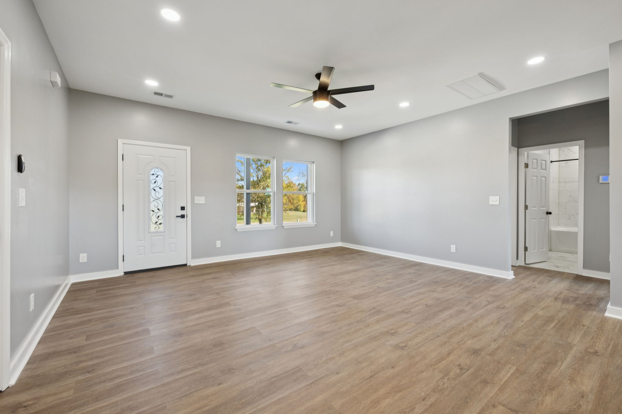 10154 Rocky Point Road Bon Aqua, TN 37025 - Photo 7 of 26 an empty room with wooden floor a ceiling fan and windows