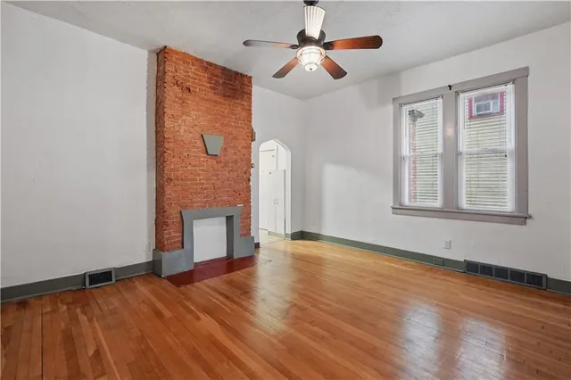 a view of an empty room with window and wooden floor