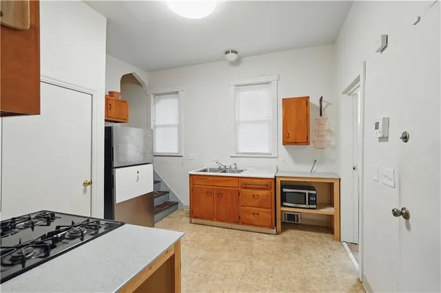 a kitchen with stainless steel appliances a stove a refrigerator a sink a counter space and cabinets