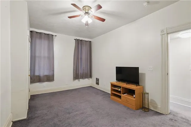 a room with a flat screen tv and a ceiling fan