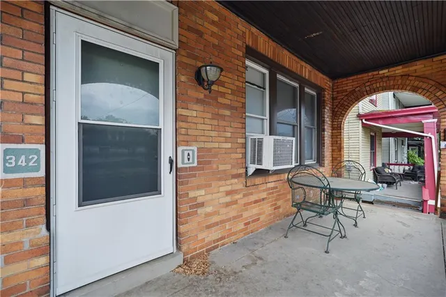 a view of a brick house with chairs and table in a patio