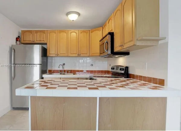a kitchen with stainless steel appliances granite countertop a refrigerator sink stove and white cabinets with wooden floor