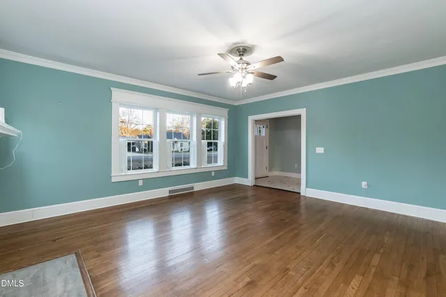 a view of an empty room with wooden floor and a window