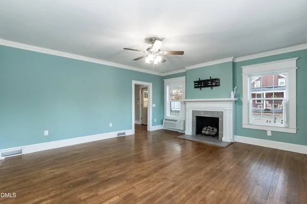 a view of an empty room with window and wooden floor