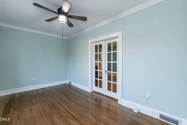 an empty room with wooden floor fan and windows