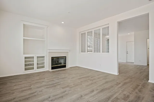 an empty room with wooden floor fireplace and windows
