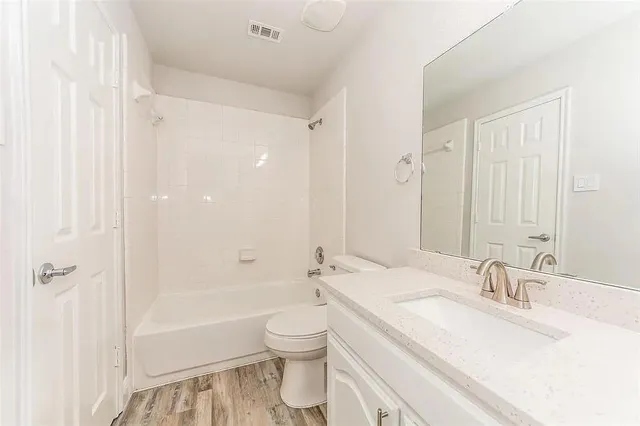a bathroom with a bathtub shower sink vanity mirror and toilet