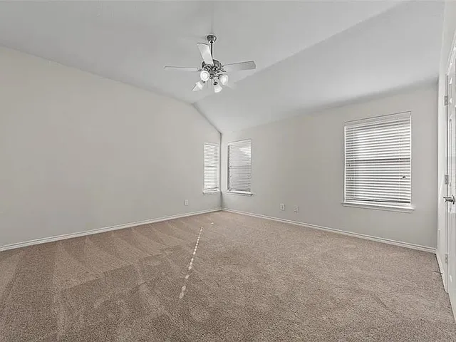 an empty room with windows and chandelier fan