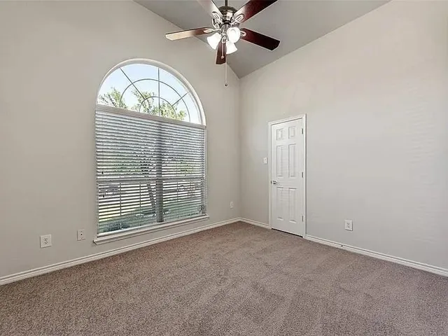 an empty room with chandelier fan window and wooden floor